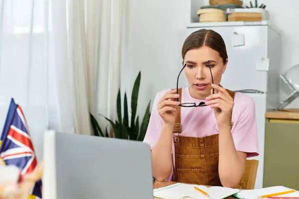 Beautiful young woman concentrates on her studies at home, surrounded by books and a laptop. — Stock Photo