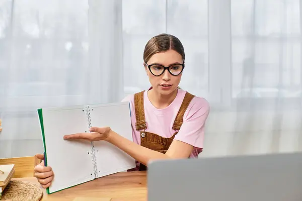 Young woman in modern attire explains concepts during an online session, displaying her notes. — Stock Photo