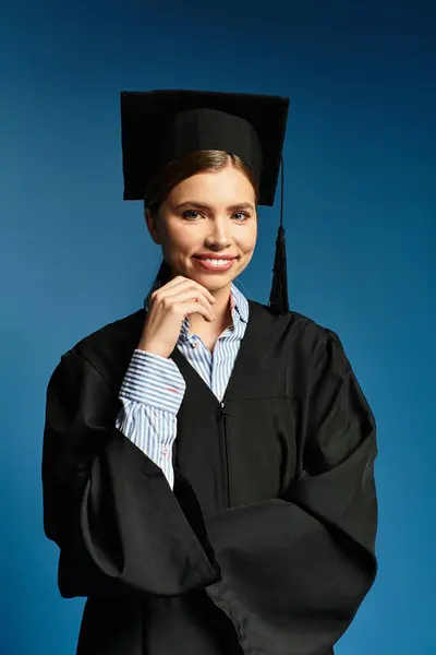 Joven mujer hermosa en una gorra de graduación y vestido sonríe con confianza contra un telón de fondo vibrante. — Stock Photo