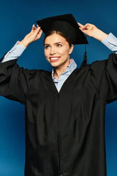 A young woman smiles as she adjusts her graduation cap, radiating excitement. — Stock Photo