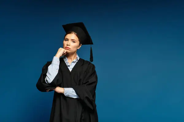 Celebrando los logros académicos, una joven con un vestido de graduación muestra una expresión de confianza. - foto de stock