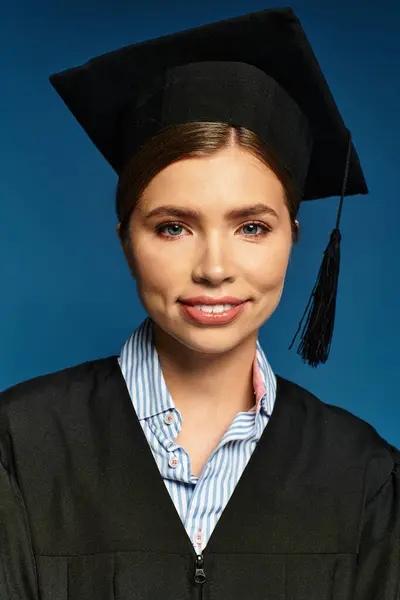 Una joven hermosa mujer orgullosamente lleva una gorra de graduación y un vestido, irradiando felicidad. - foto de stock