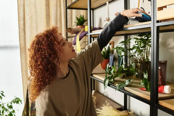 In a bright room, a talented young woman engages in DIY projects, arranging supplies on shelves. — Stock Photo