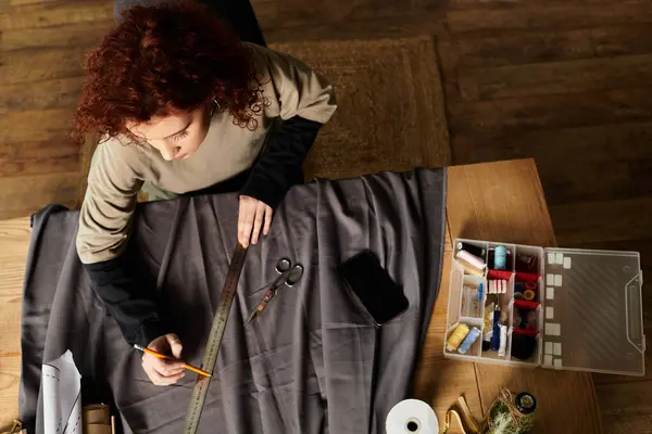 Une jeune femme mesure habilement le tissu pour son projet de bricolage, mettant en valeur son talent. — Photo de stock