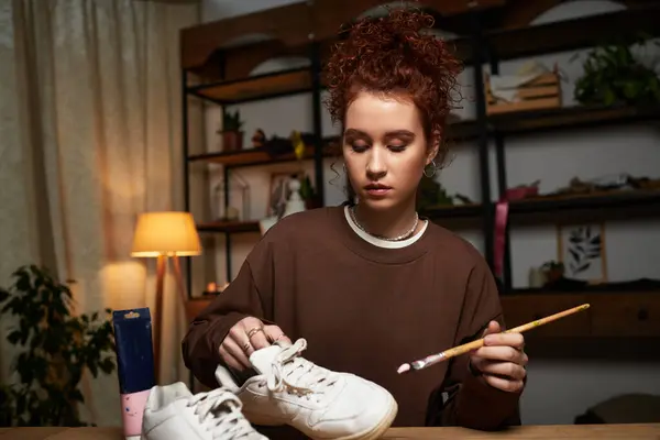 Skilled craftswoman engages in a fun project, enhancing sneakers with paint in a stylish room. — Stock Photo