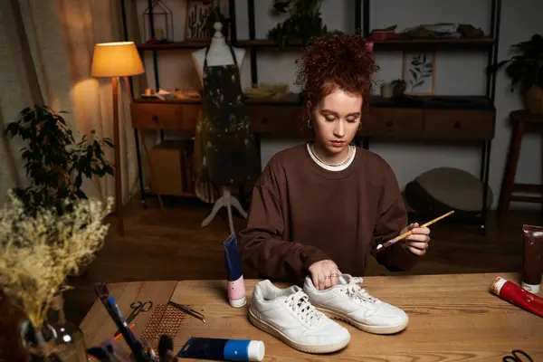 Craftswoman enjoys a DIY project, painting sneakers at a beautifully arranged workspace. — Stock Photo