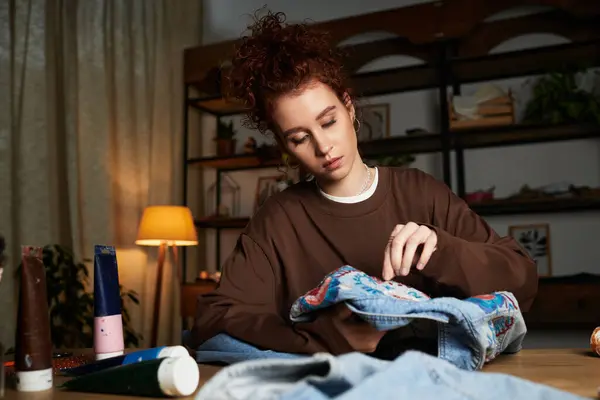 Une jeune femme crée des motifs colorés sur le denim dans son espace de travail élégant. — Photo de stock