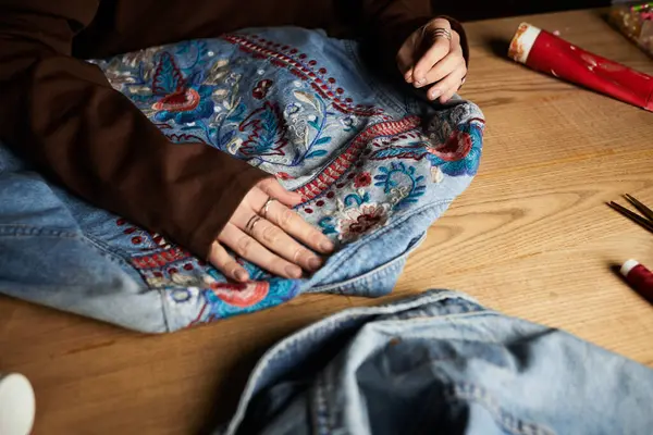 Une jeune belle femme met en valeur son talent de bricoleuse en travaillant sur une pièce en denim brodé. — Photo de stock