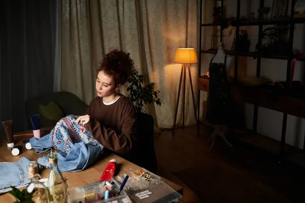 A skilled craftswoman enhances a denim piece with her unique stitching at home. — Stock Photo