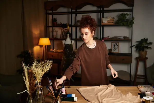 Une jeune femme profite d'un projet de bricolage dans son élégant espace de travail à la maison pendant la soirée. — Photo de stock