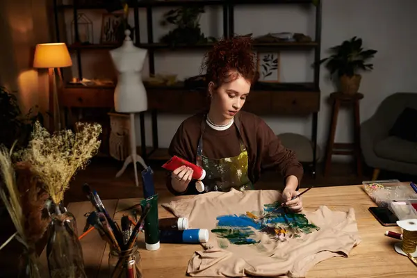 Craftswoman enthusiastically paints vibrant colors onto a fabric piece in her artistic workspace. — Stock Photo