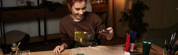 Artesana disfruta de un momento de creatividad, documentando su proceso artístico en un acogedor espacio interior. - foto de stock