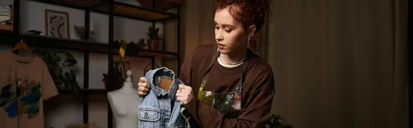 Young craftswoman passionately designs a unique denim jacket while surrounded by artistic decor. — Stock Photo