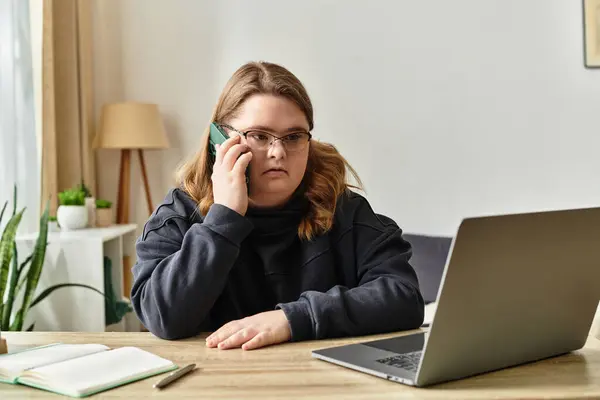 A confident young woman with Down syndrome sits at home, happily chatting on her phone. — Stock Photo