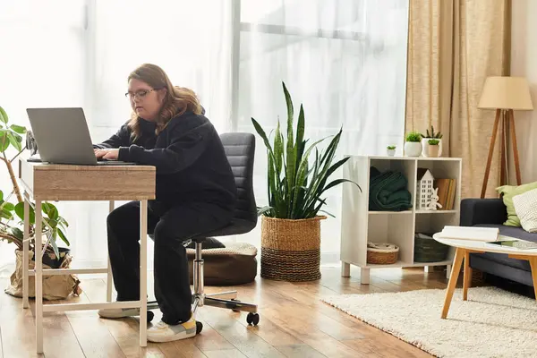 Bright indoor space with a young woman with Down syndrome focused at her desk among plants. — Stock Photo