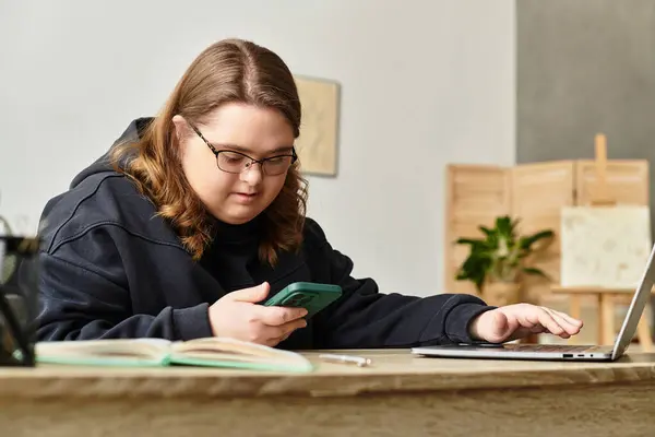 In a cozy home, a strong young woman with Down syndrome uses her phone and laptop. — Stock Photo