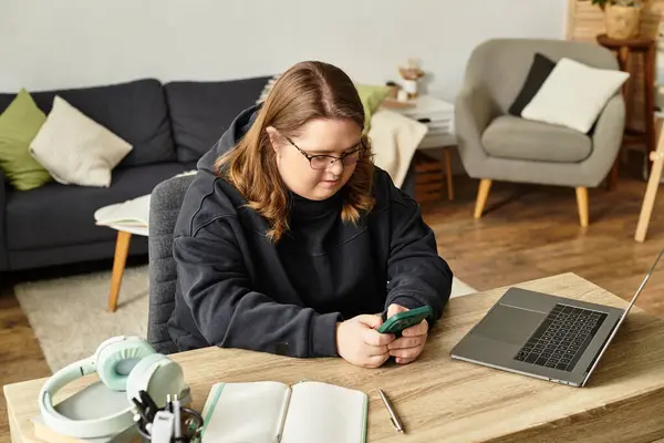 A young woman with Down syndrome confidently uses her smartphone in a cozy living space. — Stock Photo