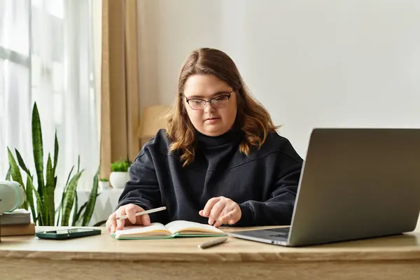 In a cozy home, a young woman with Down syndrome studies with great determination. — Stock Photo