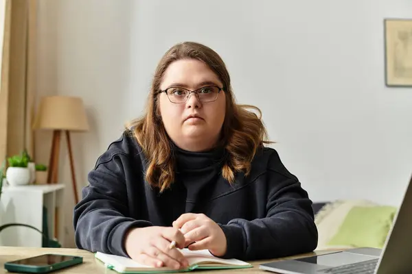 Уютная молодая женщина с синдромом Дауна пишет в блокноте дома. — стоковое фото