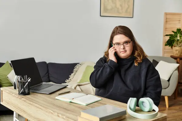 In a cozy home, a young woman with Down syndrome chats confidently on the phone at her desk. — Stock Photo