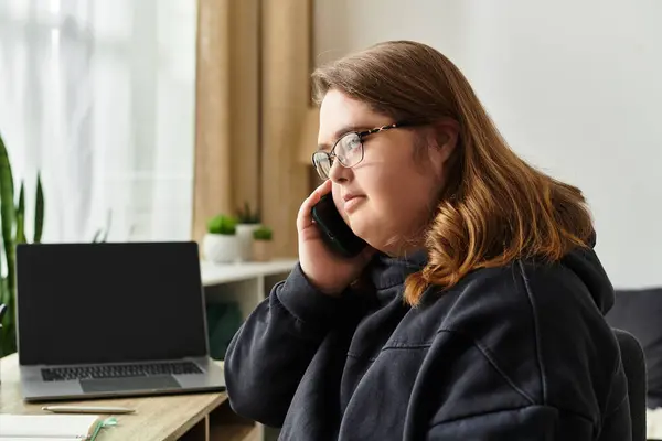 A young woman with Down syndrome engages in a warm phone conversation at home, looking relaxed. — Stock Photo