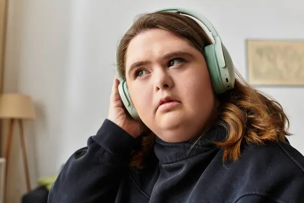 Une jeune femme détendue à la maison écoute de la musique avec écouteurs allumés, créant une atmosphère chaleureuse. — Stock Photo