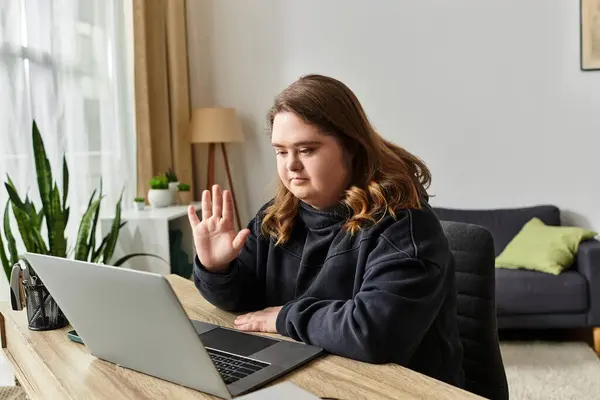 In a cozy room, a young woman with Down syndrome smiles and waves warmly. — Stock Photo