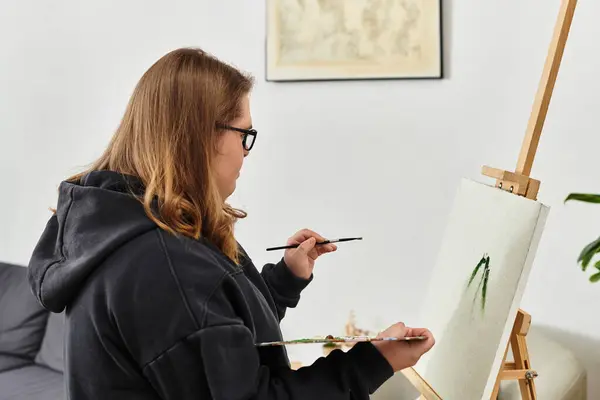 Jeune femme trisomique exprime la créativité tout en peignant dans sa maison confortable. — Photo de stock