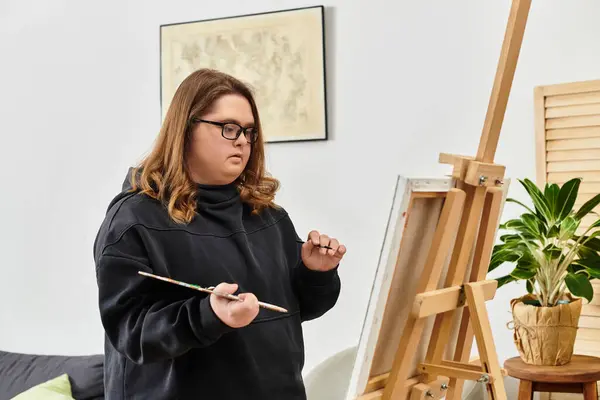 Young woman with Down syndrome enjoys painting at home, expressing her creativity with pride. — Stock Photo