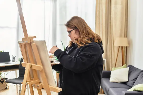 Young woman with Down syndrome expresses herself while painting in a cozy living space — Stock Photo