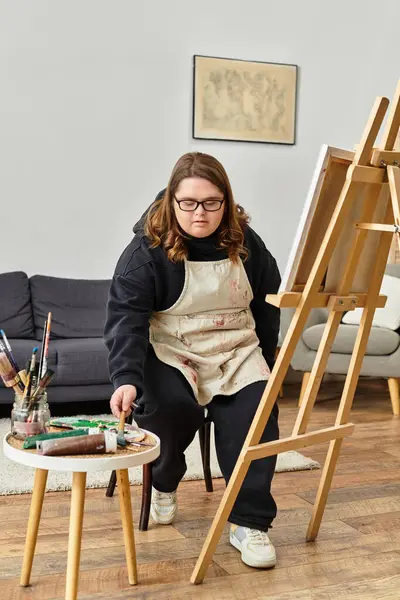A young woman with Down syndrome creates art in her home studio. — Stock Photo