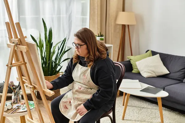 A young woman with Down syndrome enjoys painting comfortably at home in her relaxed attire. — Stock Photo