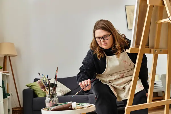 A young woman with Down syndrome shares her artistic flair while painting at home. — Stock Photo