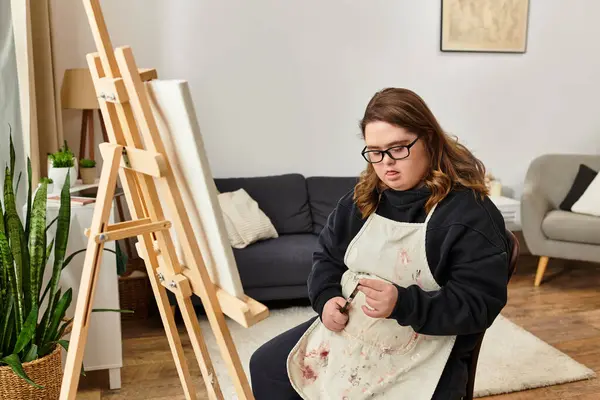 A young woman with Down syndrome expresses her creativity at home, deeply focused on her artwork. — Stock Photo