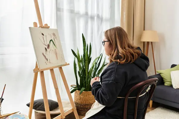 A young woman with Down syndrome creates art at home in a warm, comfy setting. — Stock Photo