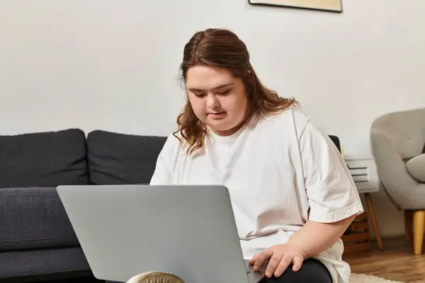 In a relaxed setting, a young woman with Down syndrome confidently uses her laptop. — Stock Photo