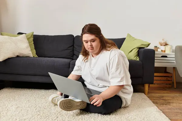 Cozy atmosphere as a confident young woman with Down syndrome engages with her laptop at home. — Stock Photo