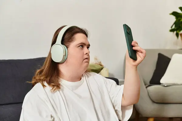 Young woman in headphones uses her smartphone at home, radiating confidence. — Stock Photo