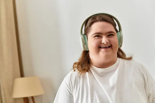 A young woman at home in comfy attire, headphones on, radiating joy and confidence. — Stock Photo