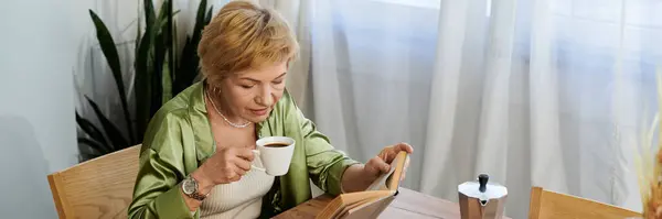 Senior woman relaxes with coffee while deeply engaged in reading a book at home. — Stock Photo