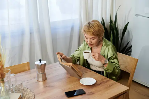 A senior woman enjoys coffee and a book at a sunlit kitchen table filled with plants. — Stock Photo