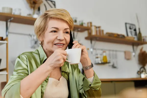 A joyful senior woman sips tea and chats happily in a cozy environment. — Stock Photo