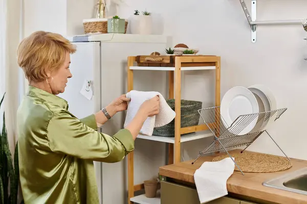 Bella donna anziana organizza armoniosamente biancheria da cucina in uno spazio caldo e invitante. — Foto stock