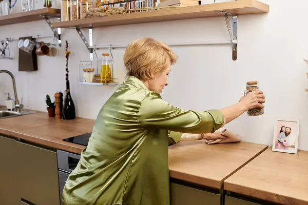 Senior woman with a warm smile prepares spices in a stylish kitchen filled with natural light. — Stock Photo