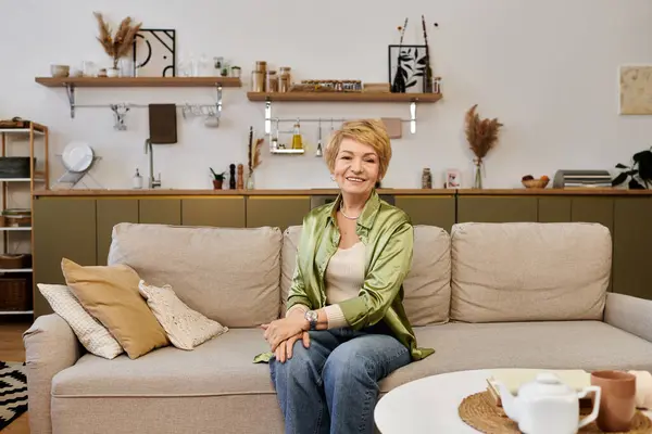 A joyful senior woman smiles warmly in her stylish living room, radiating serenity. — Stock Photo