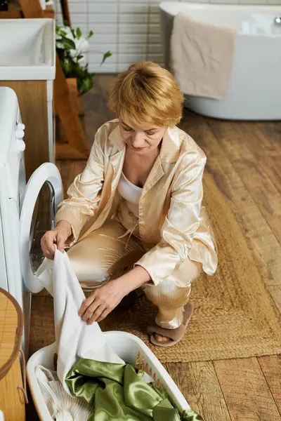 Eine schöne Seniorin kümmert sich sorgfältig um die Wäsche, umgeben vom warmen Ambiente ihres Hauses — Stockfoto