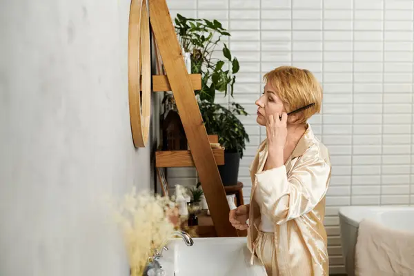 Donna anziana con i capelli corti si prepara premurosamente per la giornata, circondata da un arredamento rilassante. — Foto stock