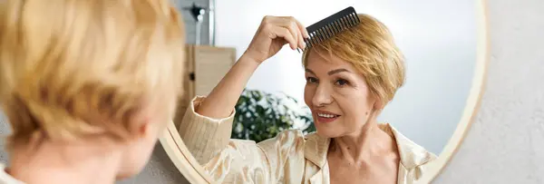 Sorridente donna anziana pettina i suoi capelli biondi corti in una stanza luminosa e invitante piena di verde. — Foto stock