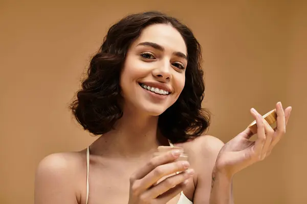 A young woman with braces happily shows her beauty skincare routine in a studio. — Stock Photo