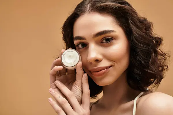 Pretty young woman demonstrates her beauty routine while showcasing her radiant skin in a studio. — Stock Photo